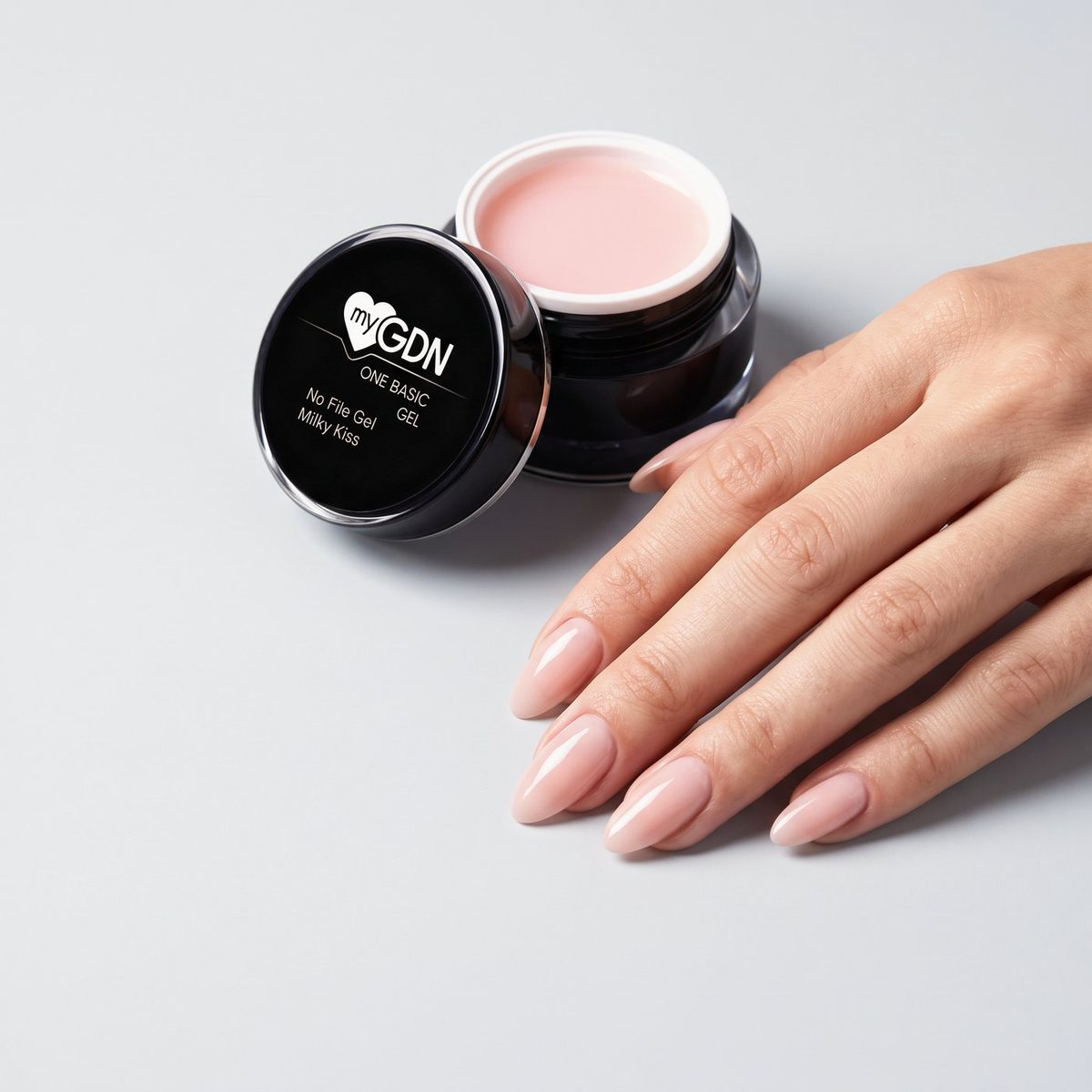Hand mit Nude-Nägeln neben einem Tiegel No File Gel Milky Kiss